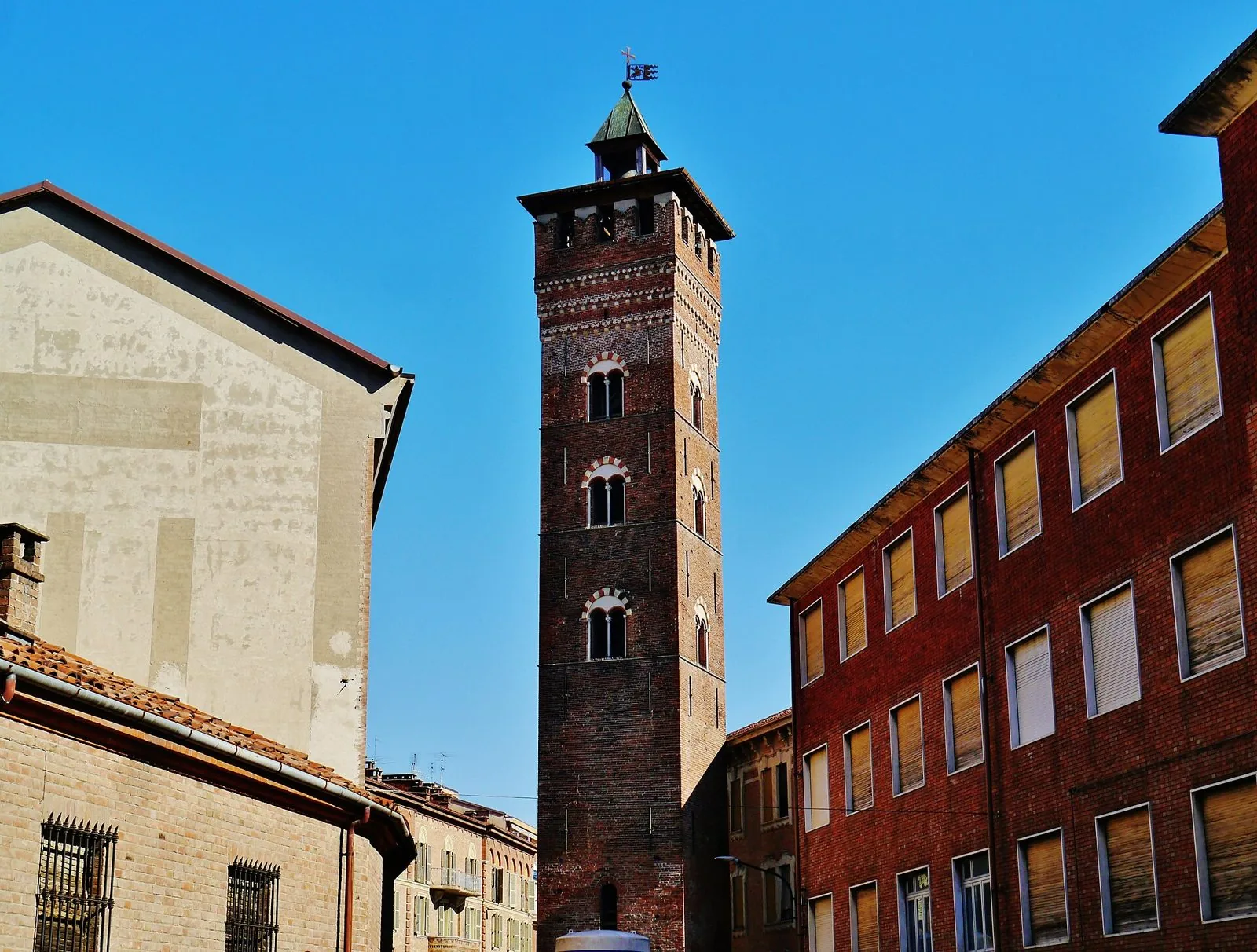 La medievale Torre Troyana in mattoni nel centro storico di Asti, sotto un cielo azzurro