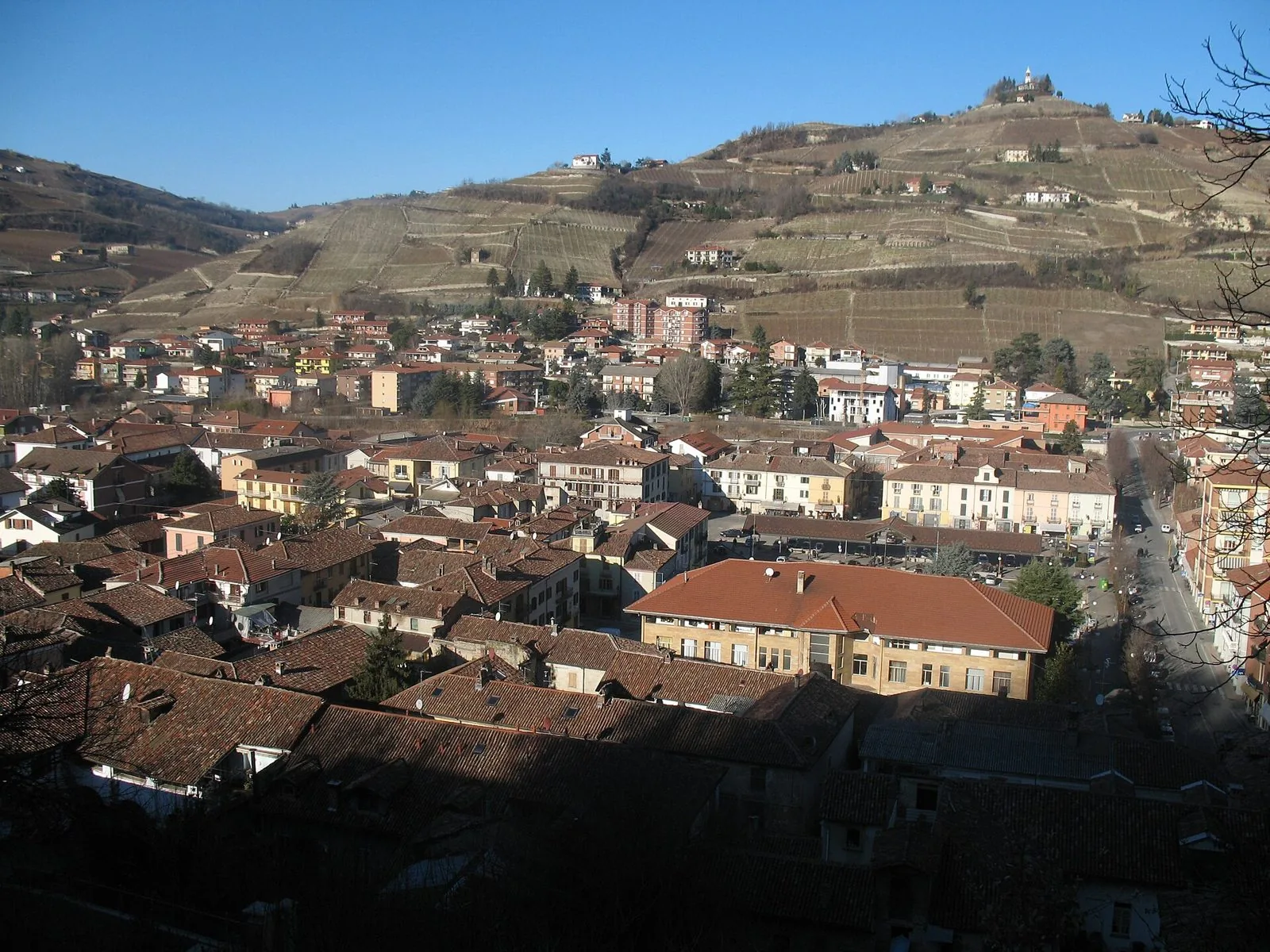 I tetti del centro di Santo Stefano Belbo e, sullo sfondo, la collina del Moncucco coperta di vigneti con la chiesetta sulla sommità