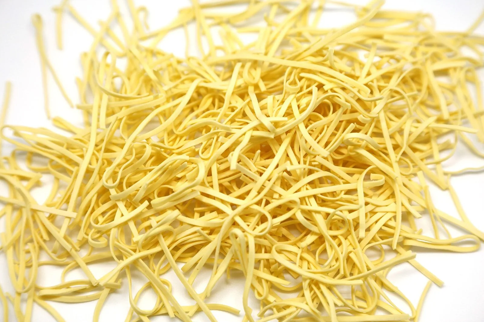 Tajarin, sottili tagliolini all'uovo di pasta fresca sparsi su un piano bianco